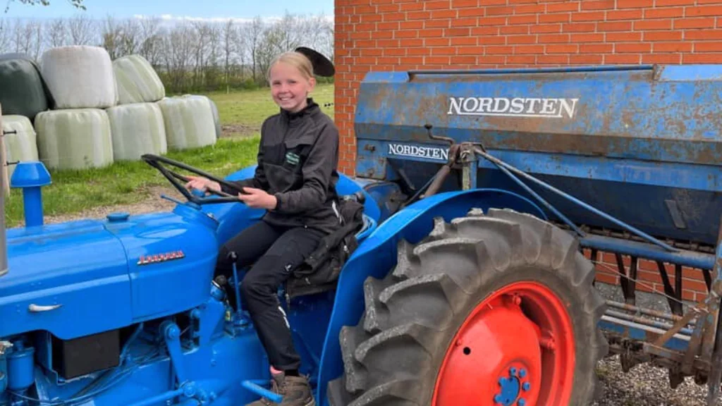 Et barn på gårdens blå veterantraktor